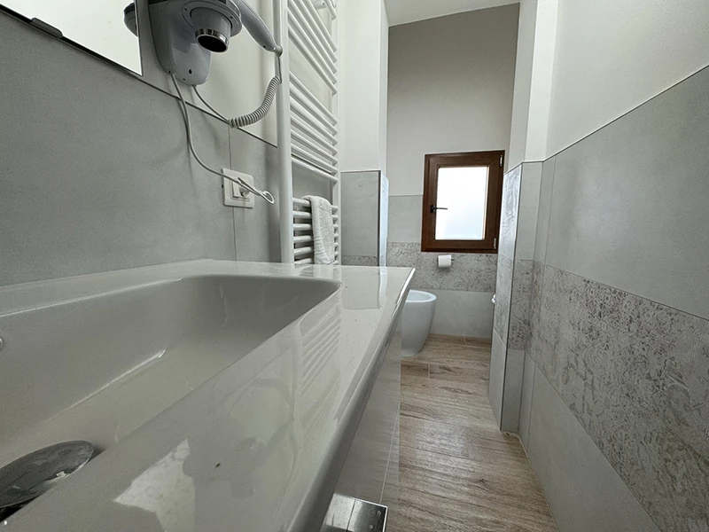 Une salle de bains moderne avec un lavabo, des toilettes, un bidet et une douche, idéale pour la routine quotidienne et la détente.