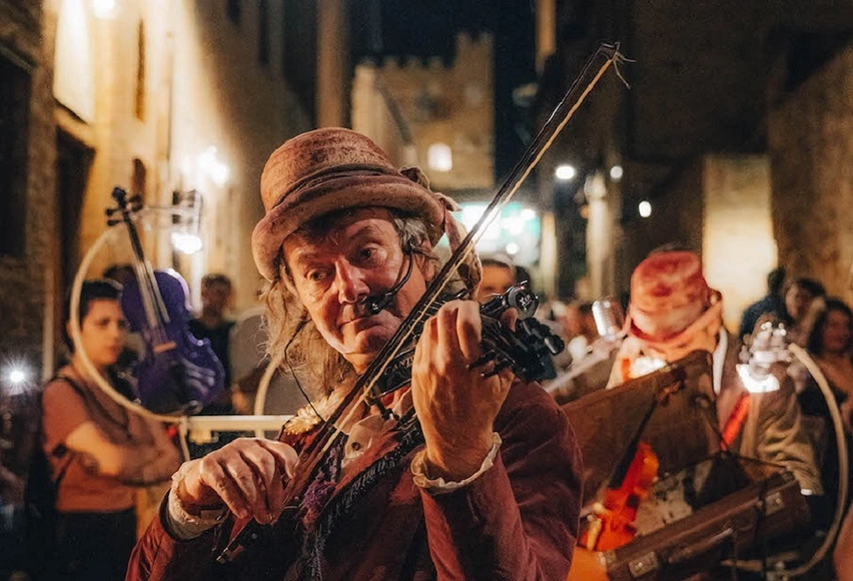 Egy kalapos utcai előadó hegedül a Mercantia Fesztiválon a toszkánai Certaldoban.